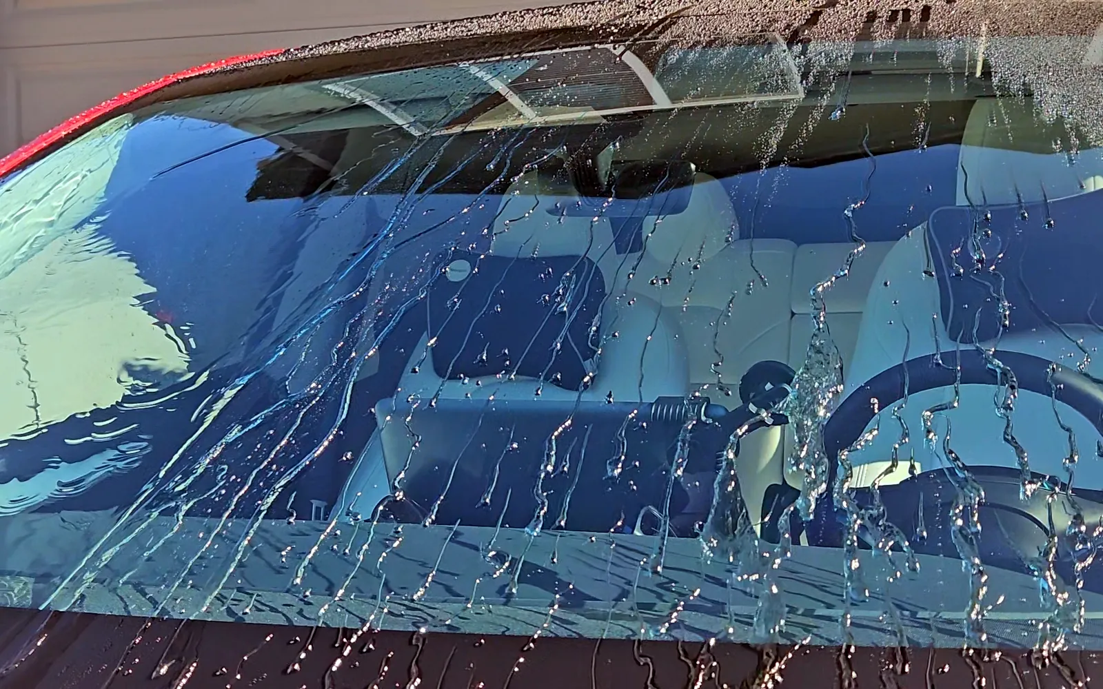 Close up of water beads and streaks on a windshield during a garden hose test