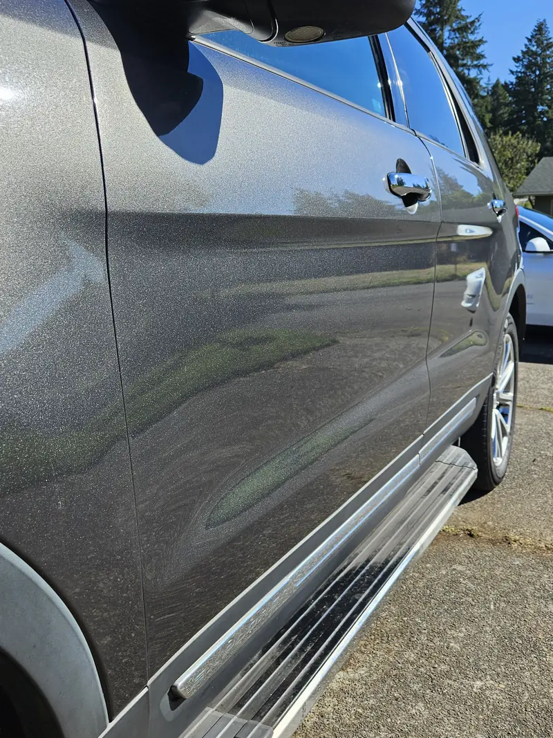 Side of a grey Ford Explorer reflecting the trees after a detail and spray sealant