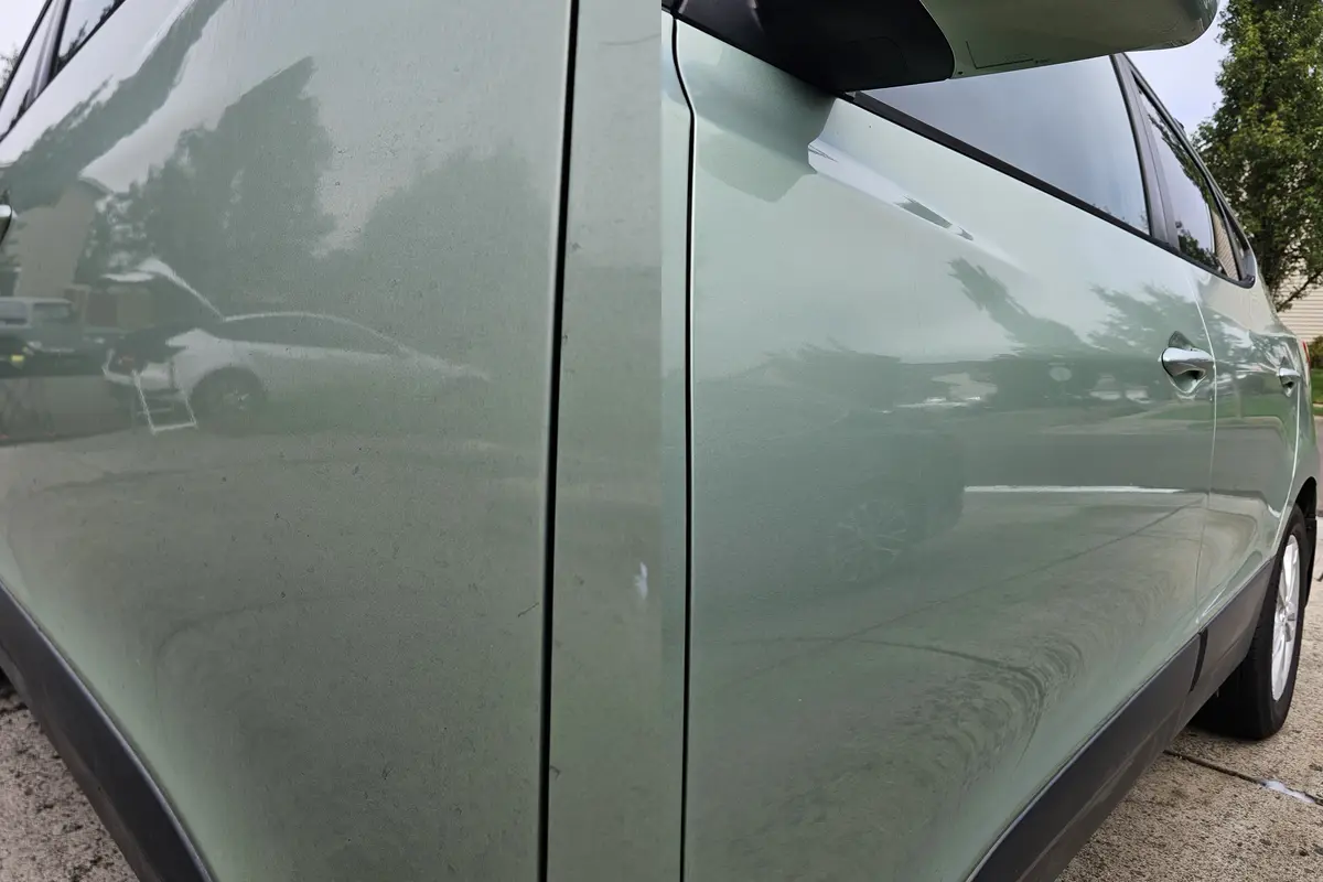 Side panel of a green Hyundai Tucson with water spots before and clean after a hand wash