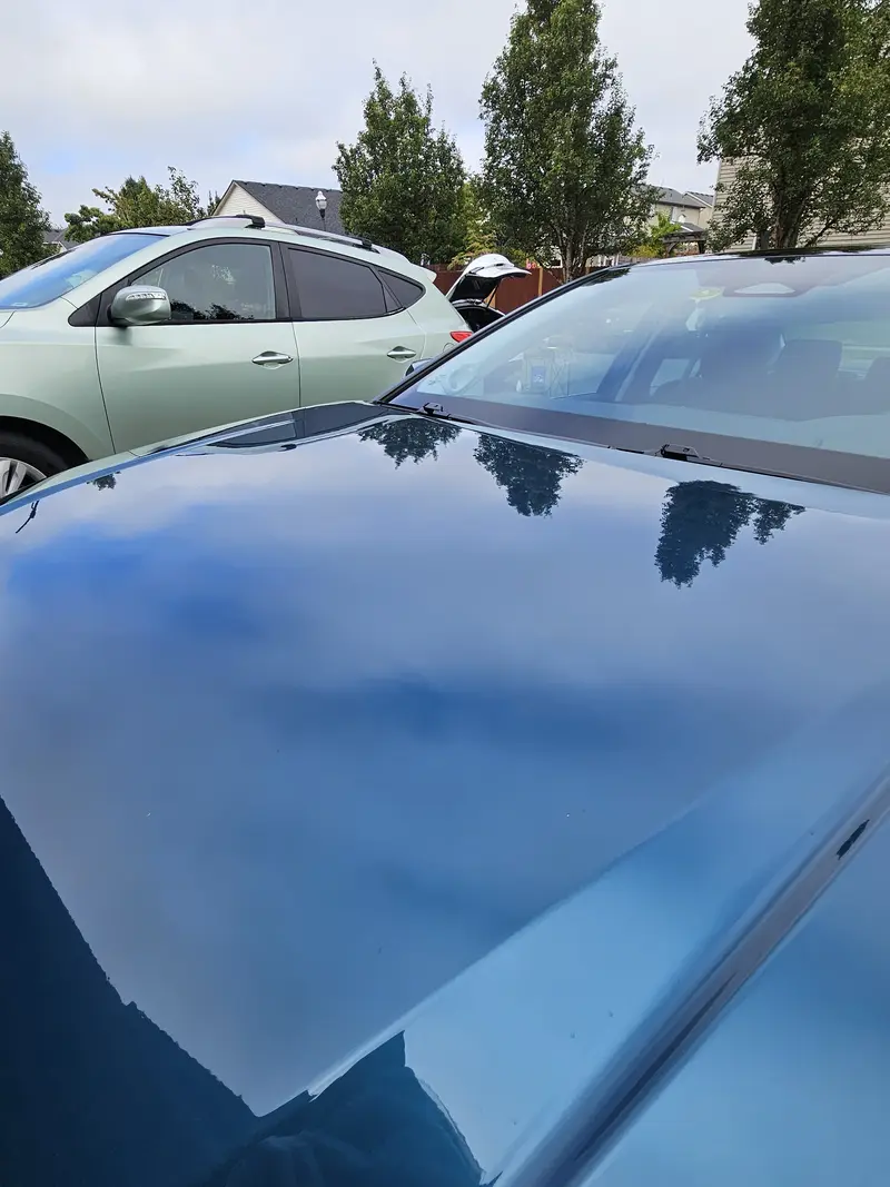 Hood of a blue 2025 Toyota Camry reflecting the sky after detailing