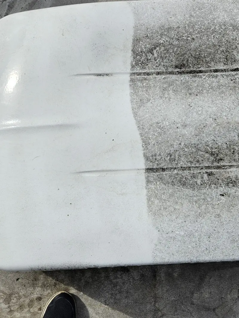 RV roof cover halfway through cleaning, clean white on one side and black grime on the other